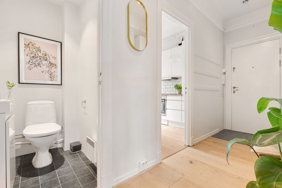 Crop anonymous person in yellow rubber protective glove wiping surface of white stylish sink with sponge and cleaning agent in modern bathroom interior